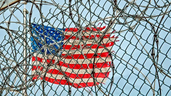 american flag behind wire fence
